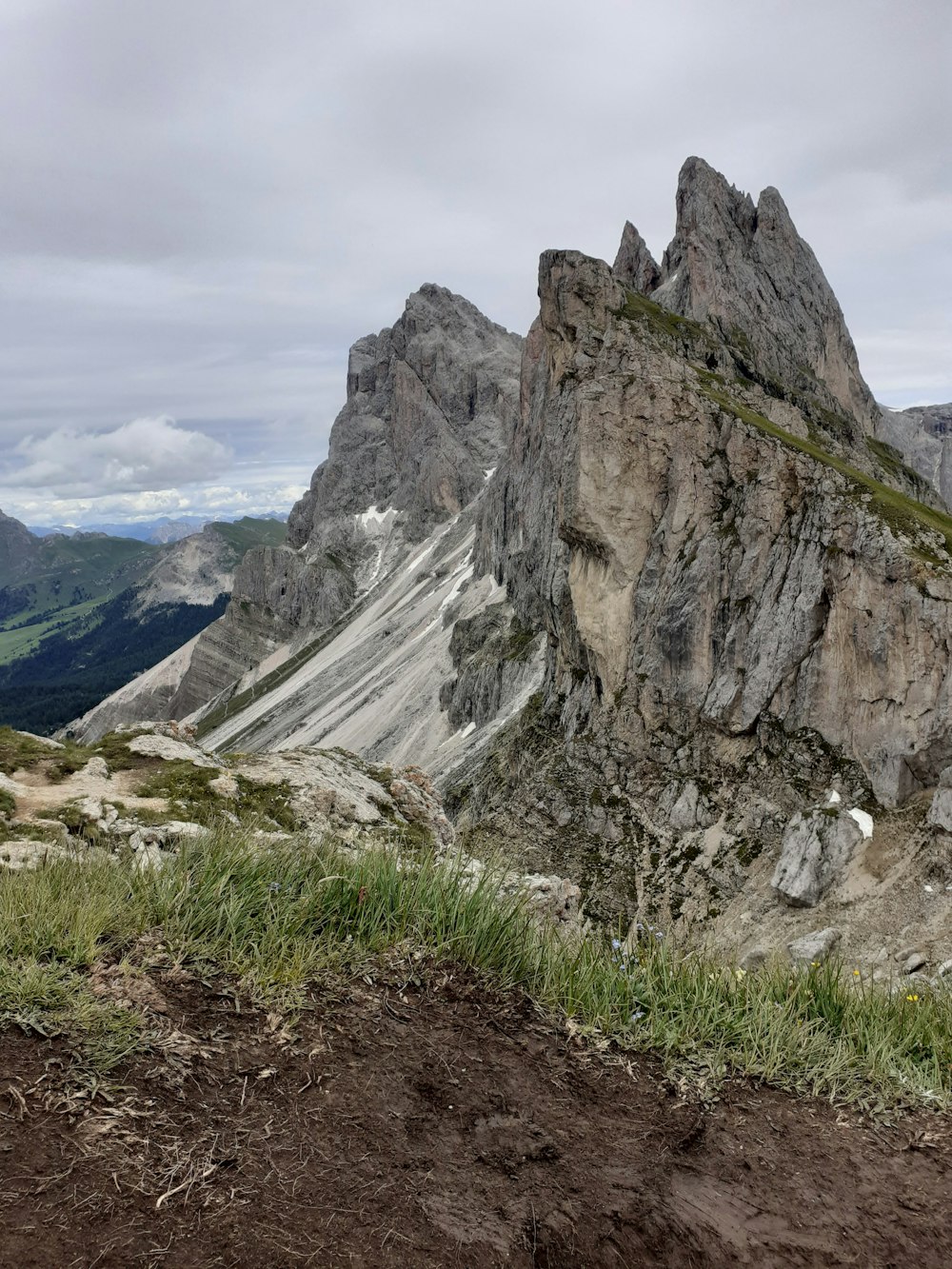 a rocky mountain with grass growing on the ground