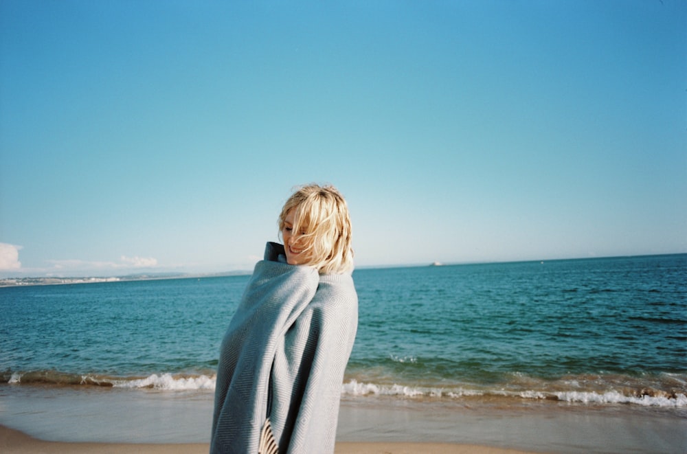 Una persona avvolta in una coperta su una spiaggia foto – Lenzuolo Immagine  gratuita su Unsplash