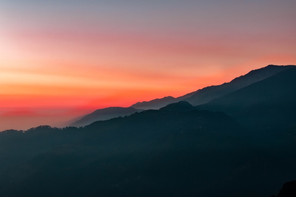 the sun is setting over a mountain range