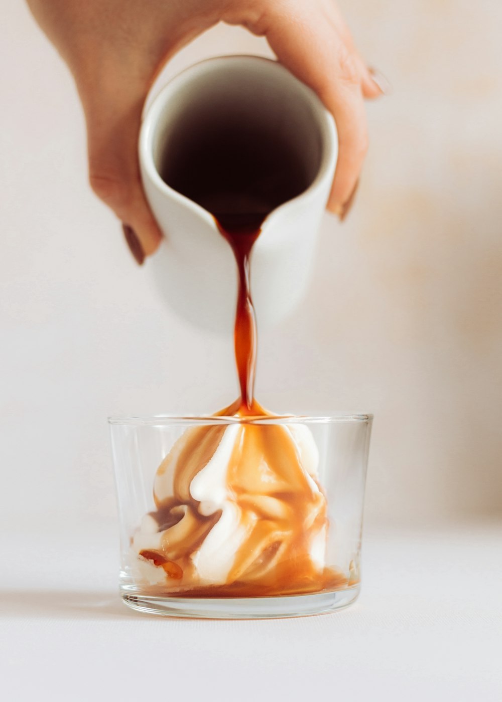 Una persona vertiendo salsa de caramelo en un vaso