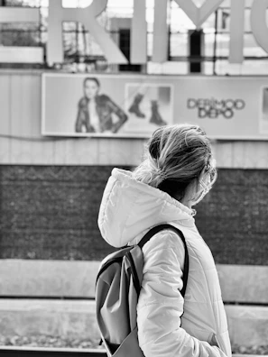 A model adjusting a Lumina hoodie while waiting at a busy subway station.