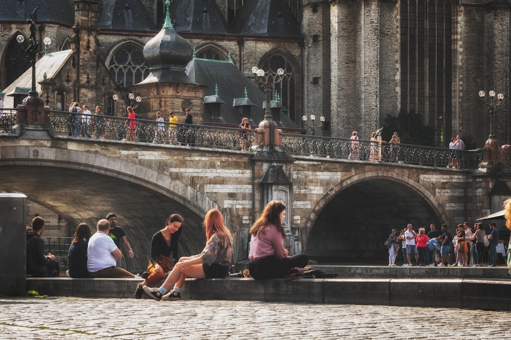 a group of people sitting on the side of a bridge