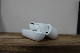 A pair of wireless earbuds resting on a wooden surface.