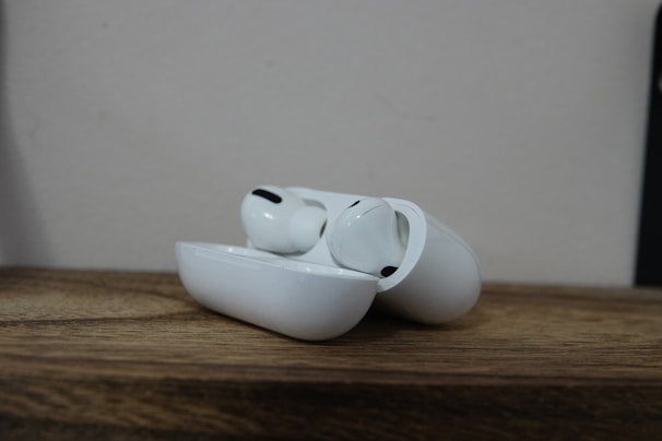 A pair of wireless earbuds resting on a wooden surface.