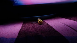 Close-up of a peach-toned keychain resting on a soft lavender fabric background.