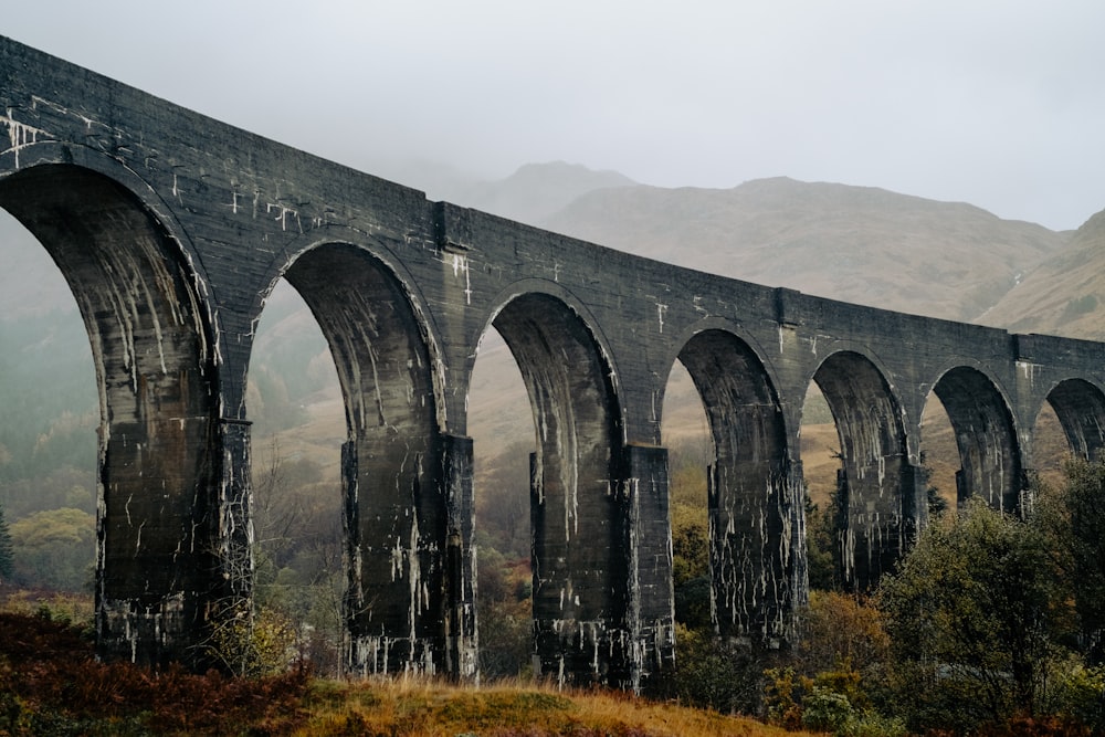 an old train bridge with arches on a foggy day