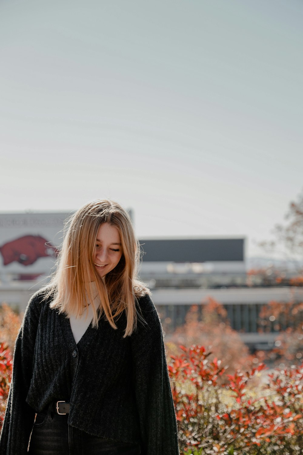 a woman standing in front of some bushes