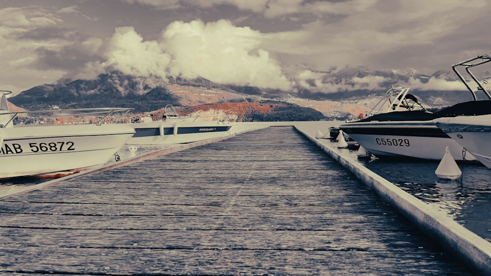 several boats docked at a pier with mountains in the background