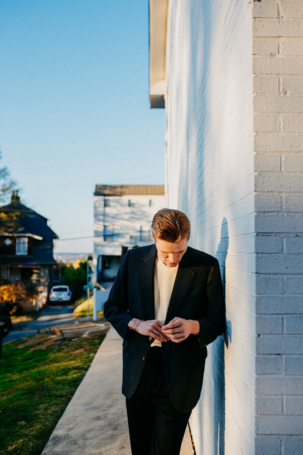 a man in a suit leaning against a wall