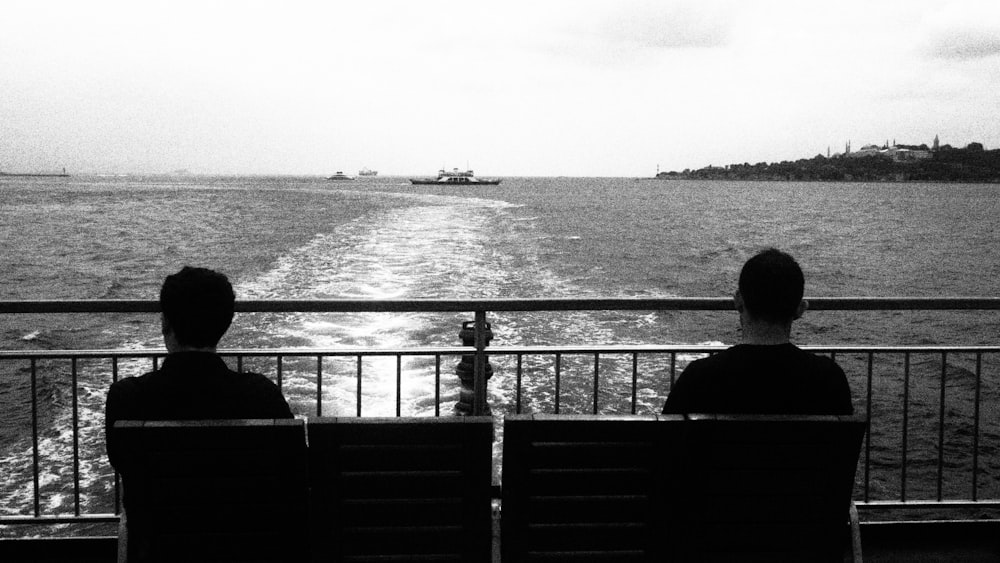 two people sitting on a bench looking out at the water