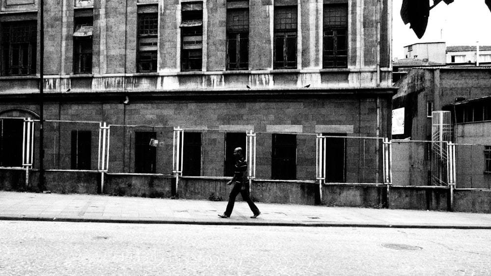 a man walking down a street past a tall building