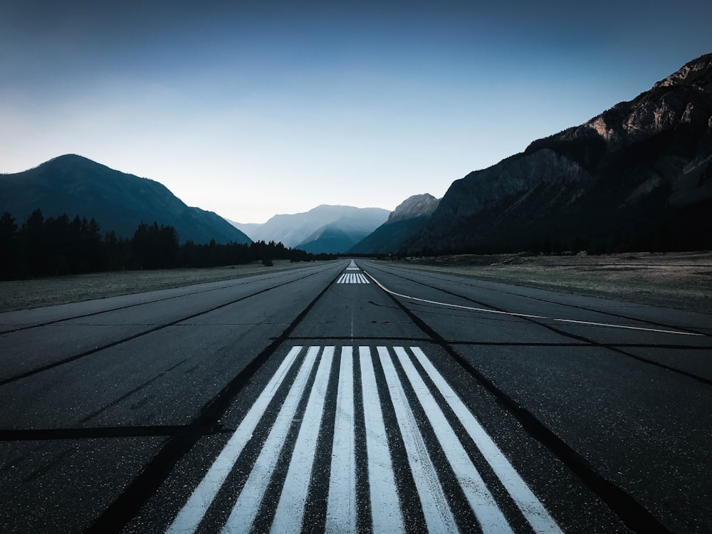 an empty runway with mountains in the background