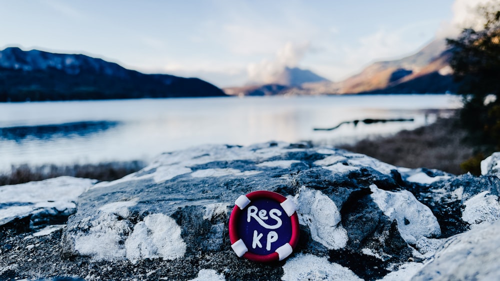 un panneau rouge et bleu assis au sommet d’un rocher à côté d’un lac