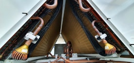 A close-up view of industrial equipment featuring a complex structure of metallic pipes and coils. Copper tubes are prominently visible, along with mechanical components and wiring neatly organized within a triangular frame.