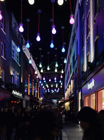 A vibrant street scene capturing everyday people engaged in lively conversation under colorful city lights.