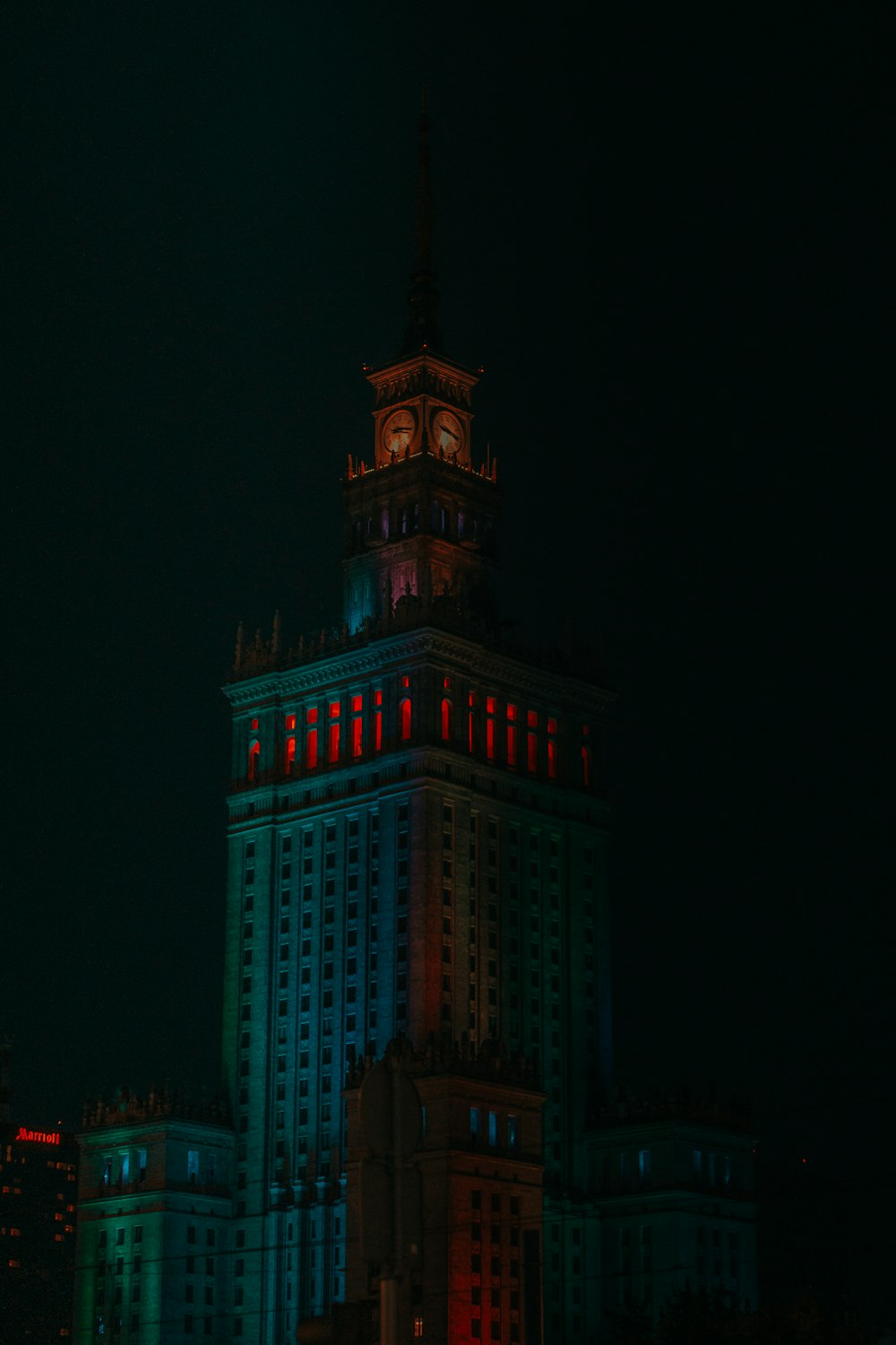 Un edificio alto con una torre del reloj iluminada por la noche
