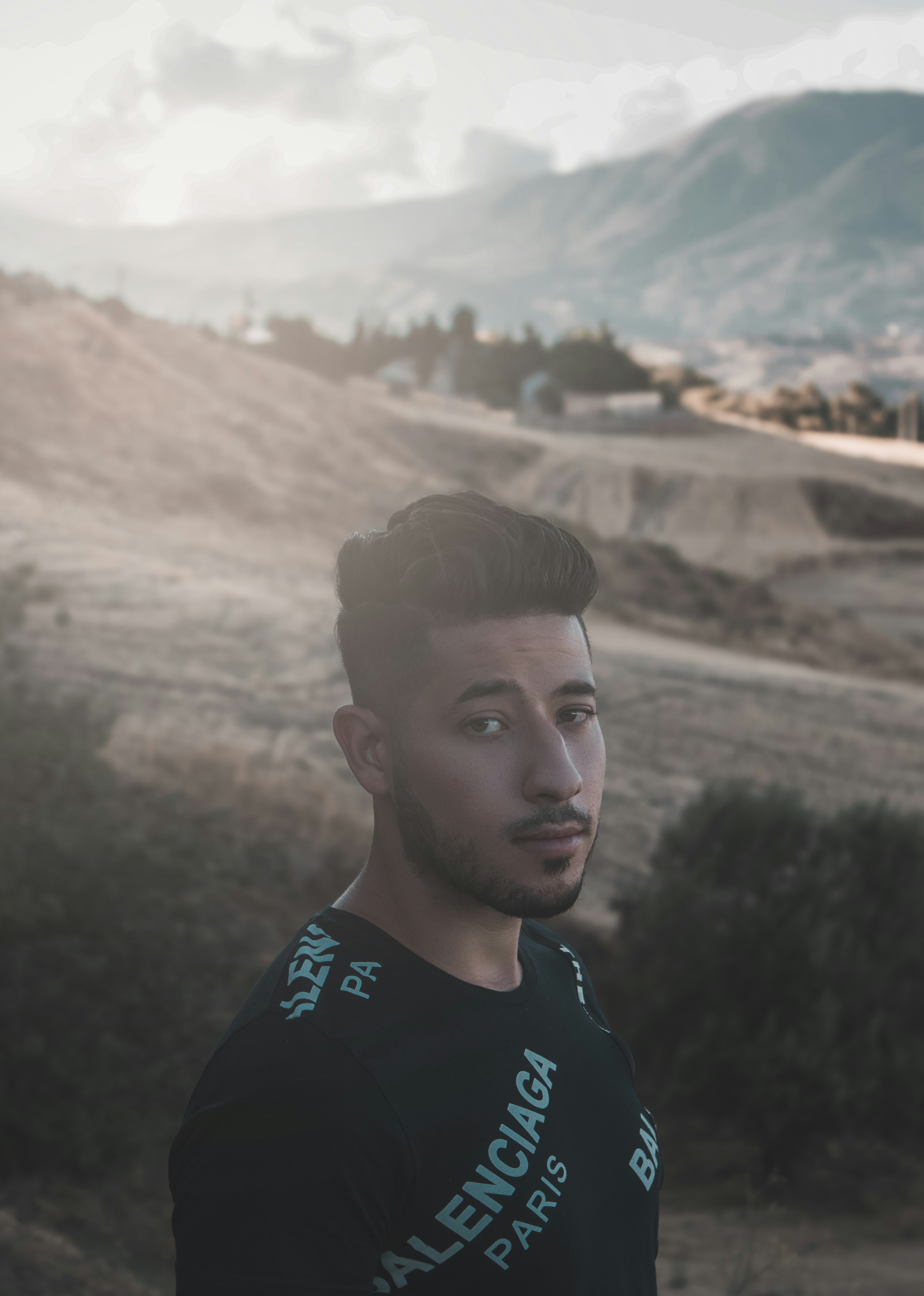 a man standing in a field with mountains in the background