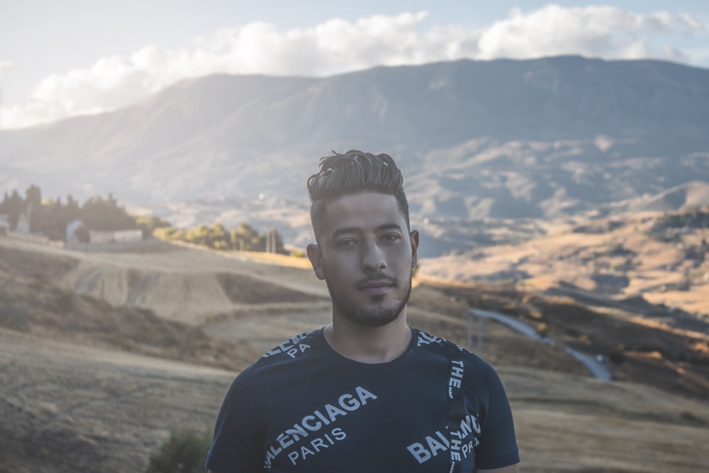 a man standing in a field with mountains in the background