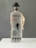 A bottle of Fiddler Vodka is displayed, featuring a frosted glass design with silhouette of a fiddler and dancers. It has a black cap shaped like a bowler hat and a tag attached to the neck. The label includes details of its production in Krakow and the alcohol volume.