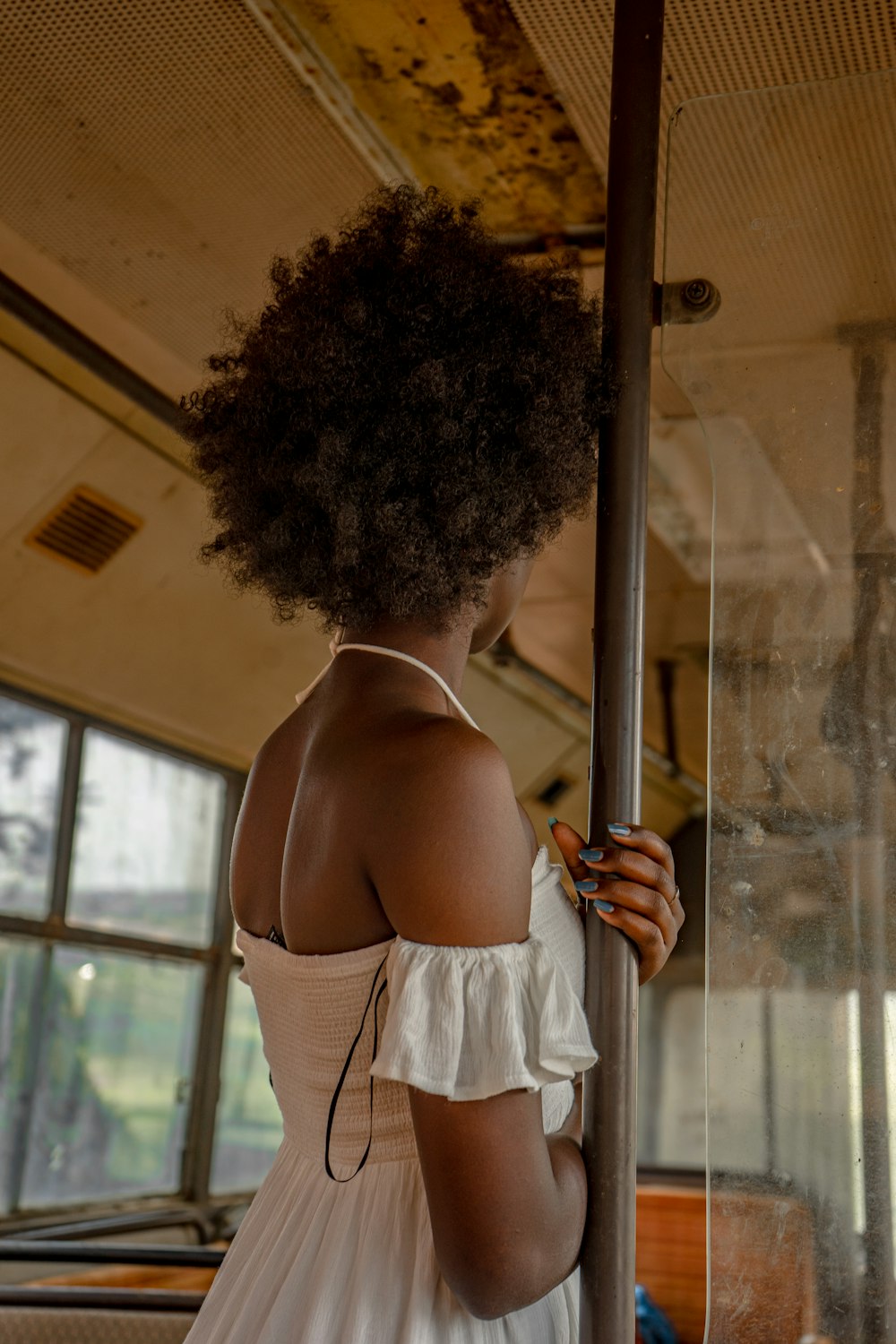 a woman in a white dress standing on a bus