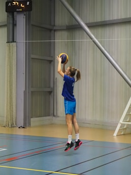 a girl in a blue shirt is playing basketball