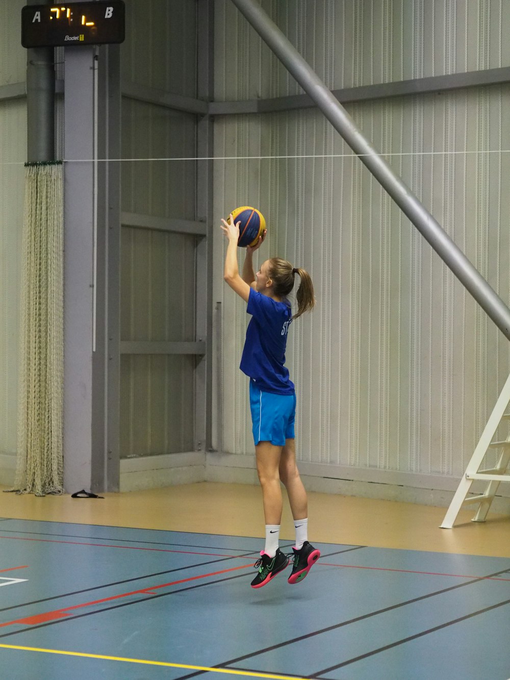 a girl in a blue shirt is playing basketball