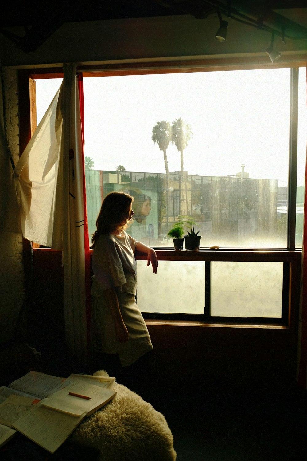 a woman standing in front of a window looking out