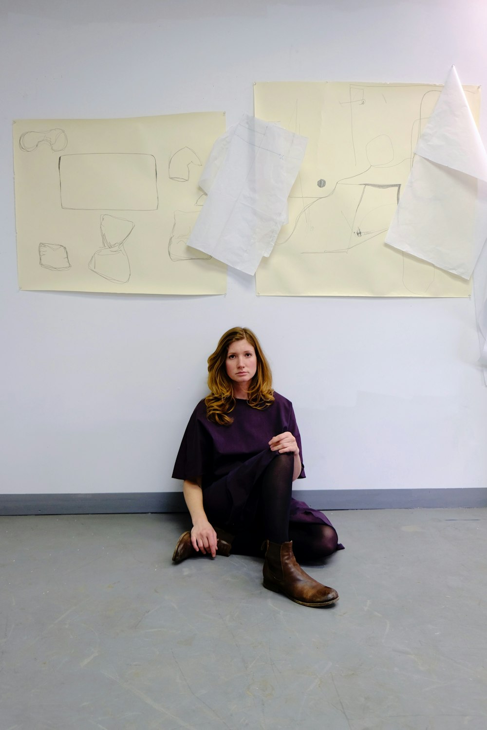 a woman sitting on the floor in front of a wall