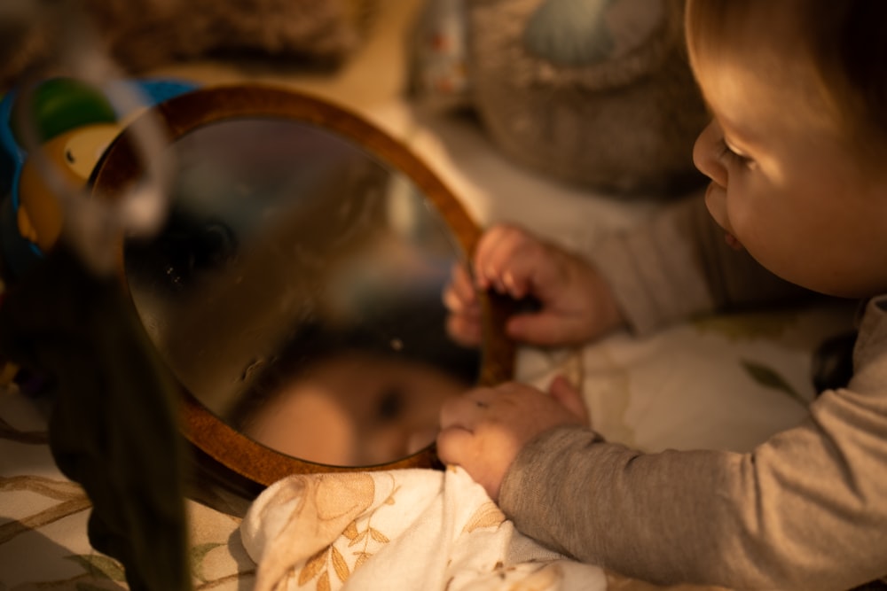 a little boy that is looking at a mirror