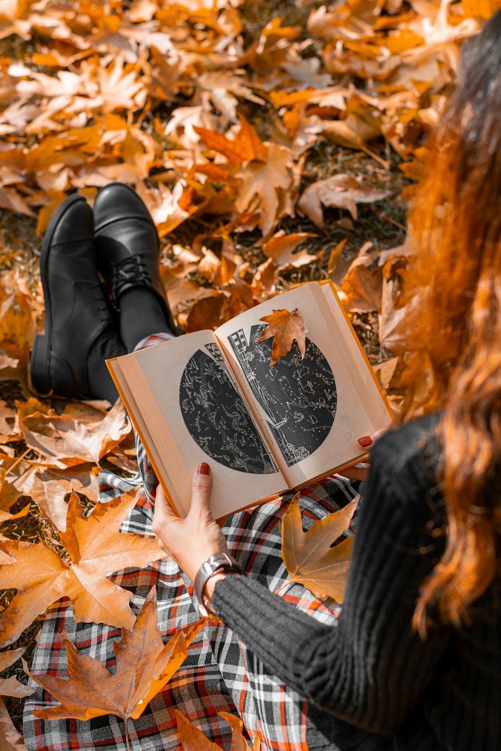 a woman laying on the ground reading a book