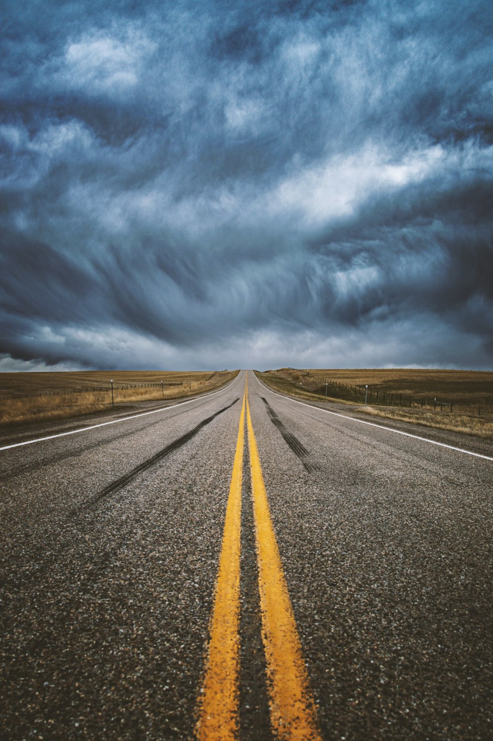 a long straight road stretches into the distance under a cloudy sky