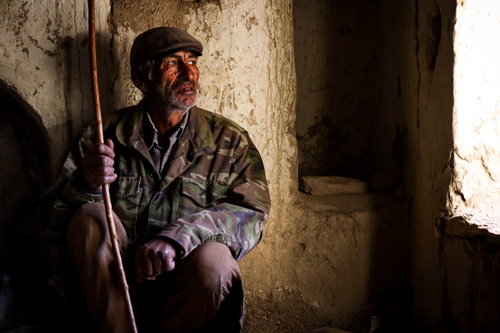 a man sitting on the ground holding a stick