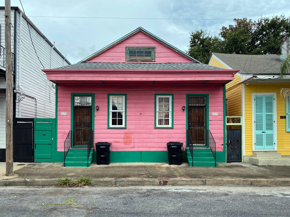 a pink house with green trim on a street corner
