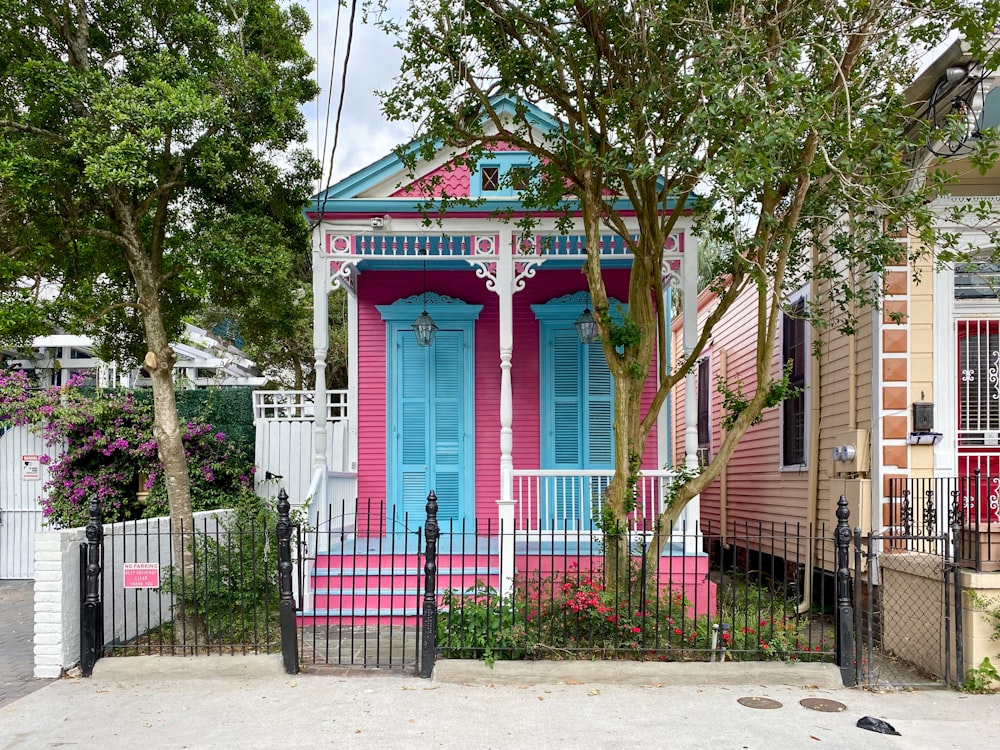 a pink and blue house with a black fence