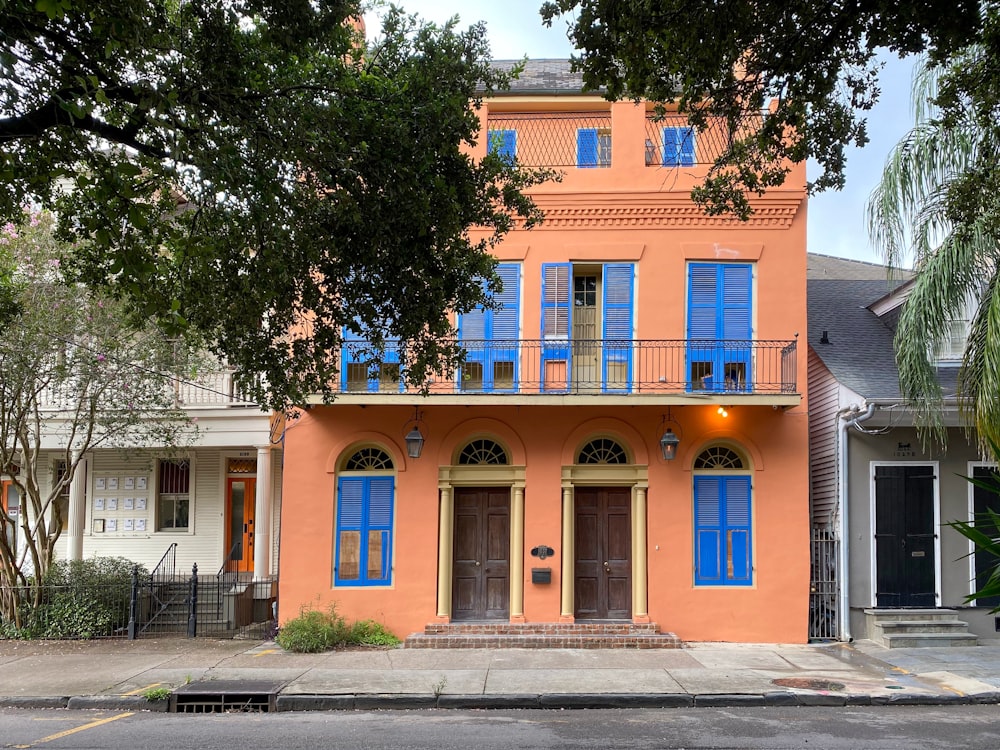 an orange house with blue shutters and a balcony