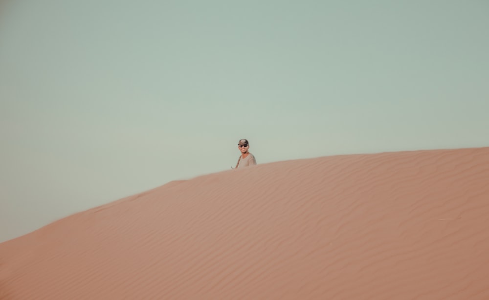 a man standing on top of a sand dune