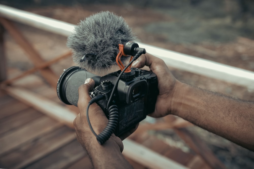 a person holding a camera with a microphone attached to it
