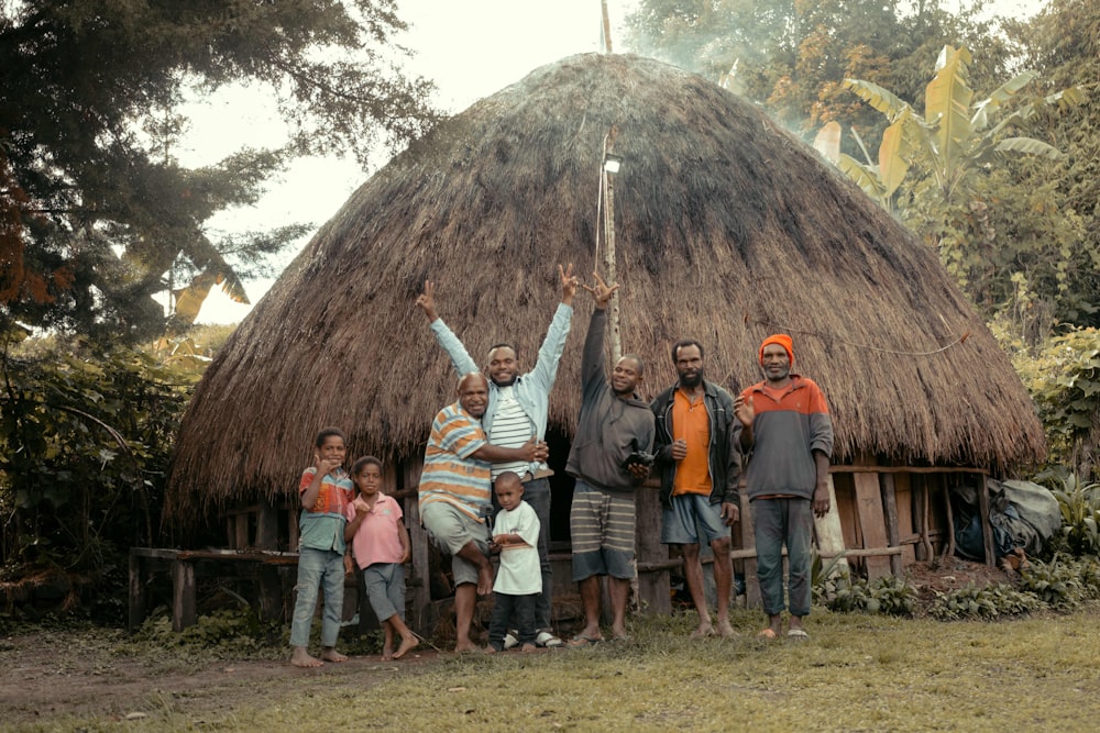 a group of people standing in front of a hut