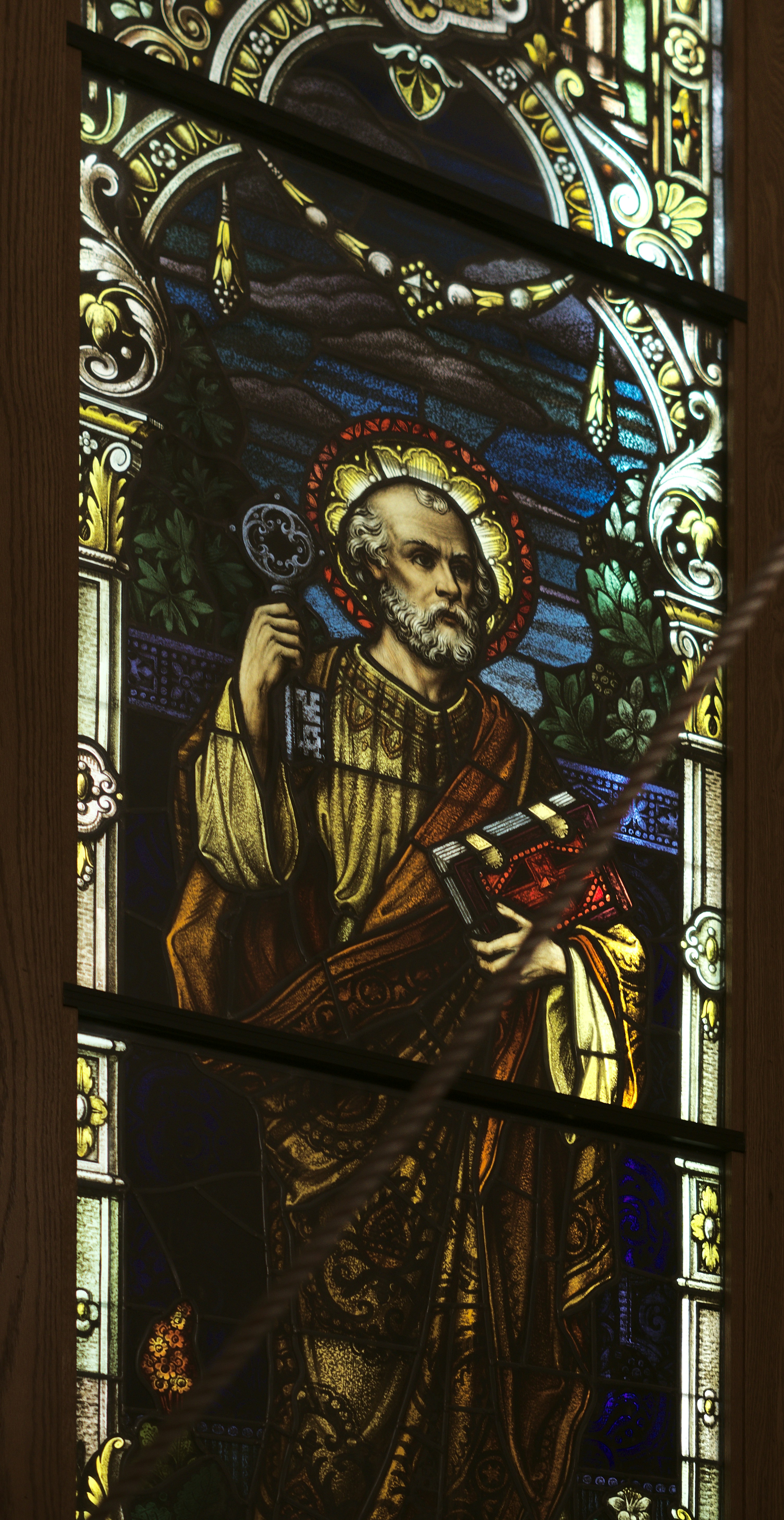 a stained glass window with a man holding a book