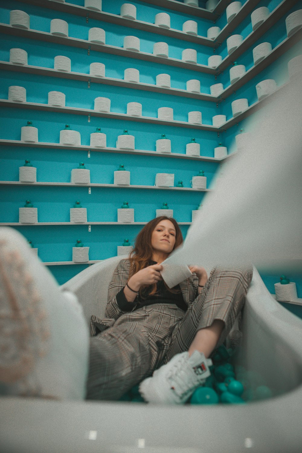 a woman sitting in a room with shelves of hats