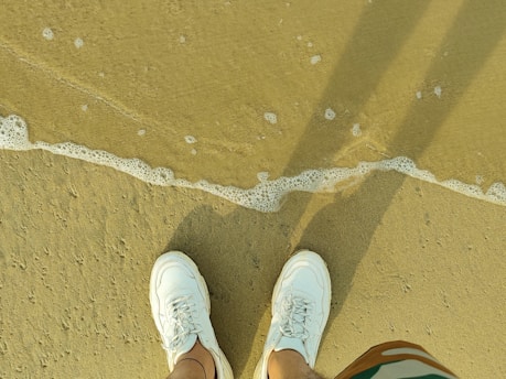 A pair of ultra-light, water-ready float shoes on a sandy beach.
