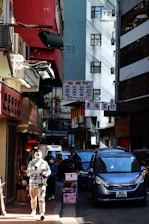 a man walking down a street next to tall buildings