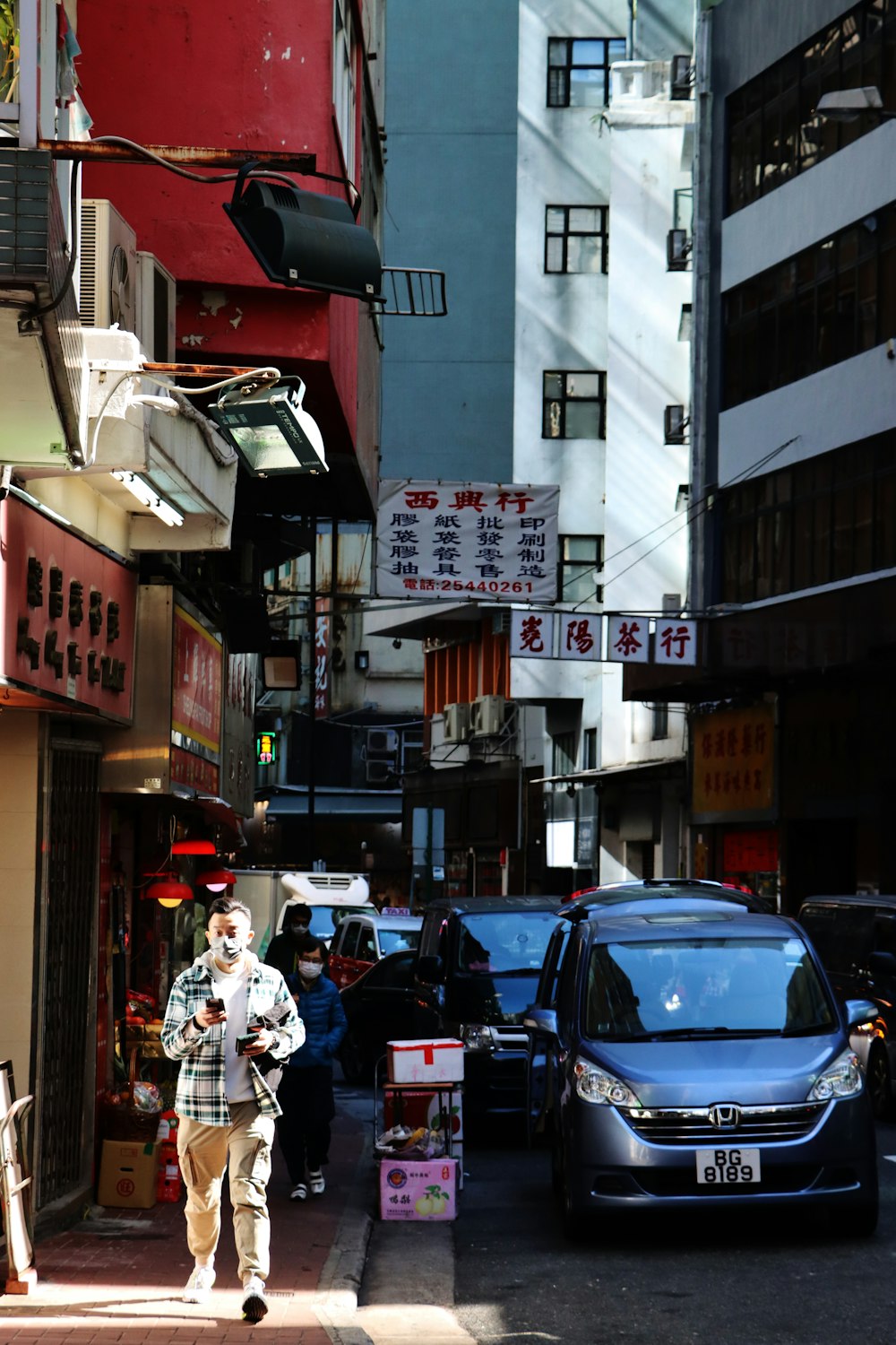 a man walking down a street next to tall buildings