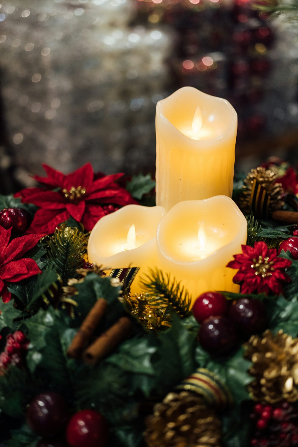 a group of three lit candles sitting on top of a christmas wreath