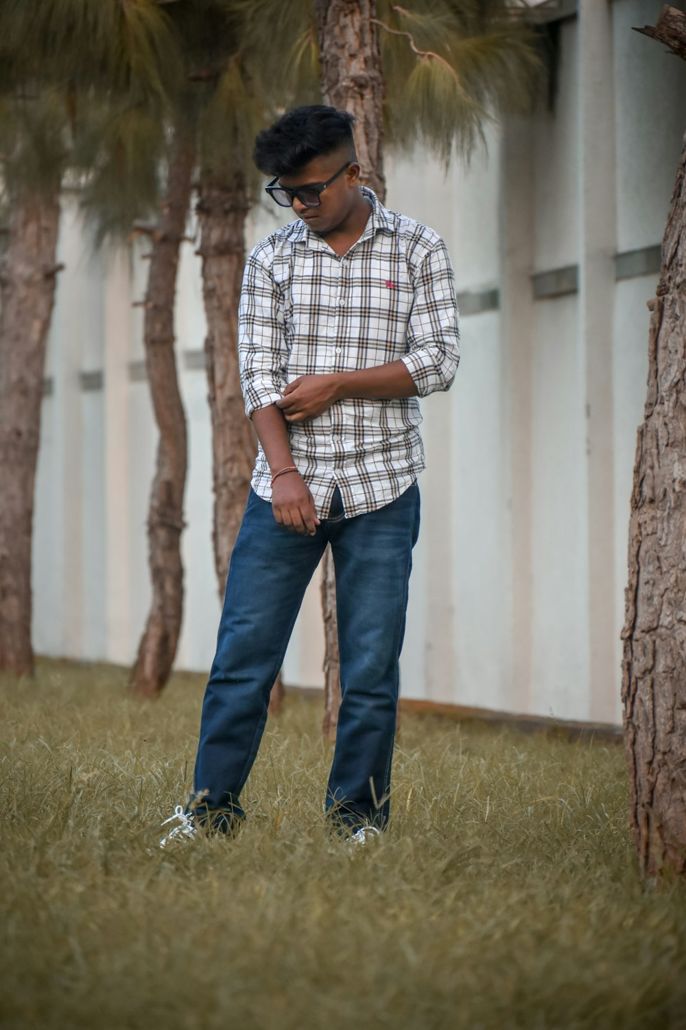 a man standing in the grass looking at his cell phone