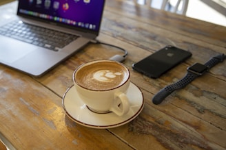 a cup of coffee on a saucer in front of a laptop
