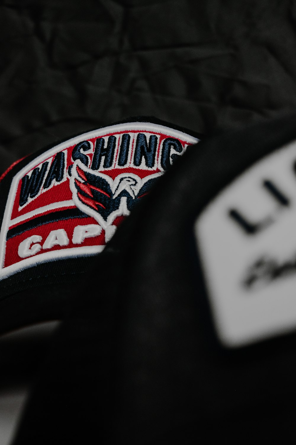 a close up of a black hat with a red and white patch