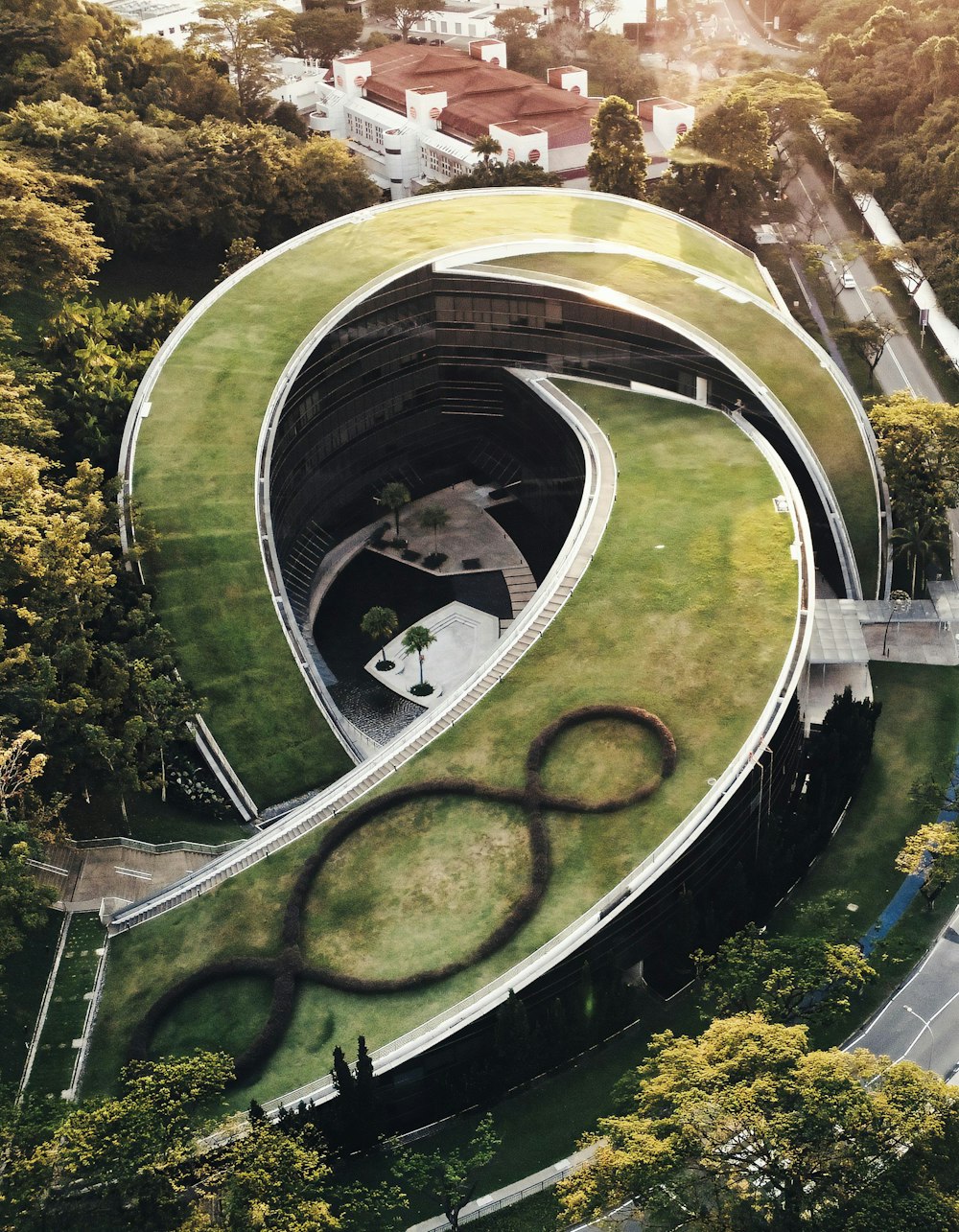 an aerial view of a curved building with a green roof