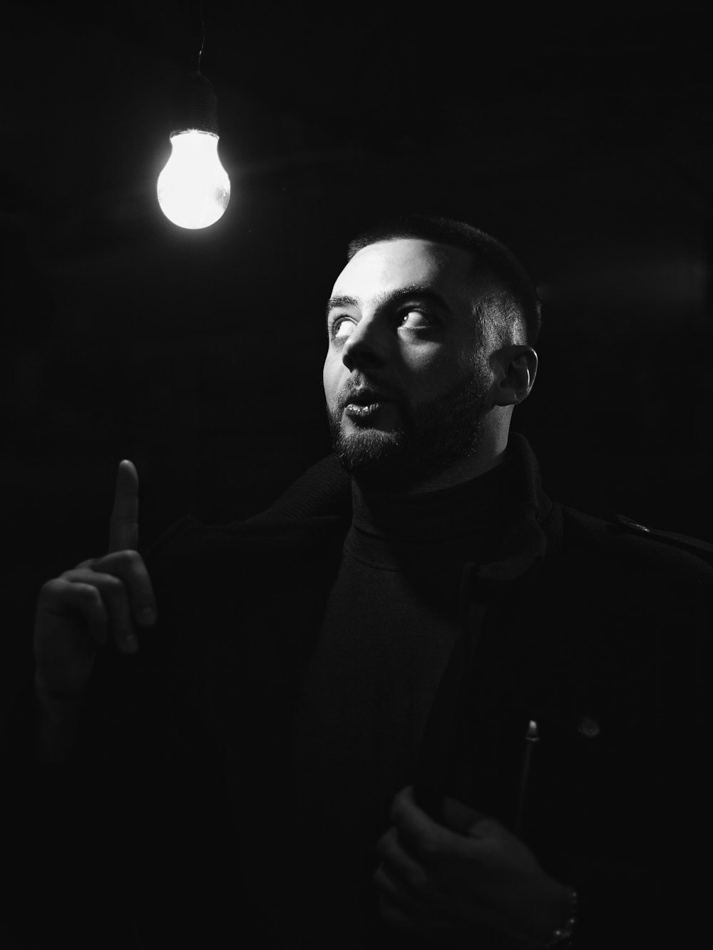 a black and white photo of a man holding a light bulb