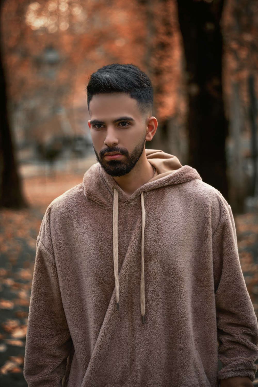 a man with a beard wearing a brown hoodie